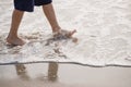 Vacation concept. Close up of boy`s legs walking on the water by the beach. Child by the sea with reflection on wet sand Royalty Free Stock Photo