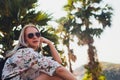 Vacation concept. Enjoying the summer. Young pretty woman in glasses sits on a palm tree over the ocean water. Royalty Free Stock Photo