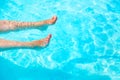 Vacation Concept. Female Sexy Legs With White Nails In Blue Water Swimming Pool. Tropical Relaxation