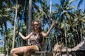 Vacation concept. Happy young woman in white dress and hat swinging at palm grove. Royalty Free Stock Photo