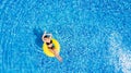 Vacation concept. Top view of slim young woman in bikini on the yellow air inflatable ring in the big swimming pool.