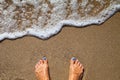 Vacation concept, women foot near sea foam at gold sand