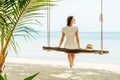 Young woman in white dress and hat swinging at a beach Royalty Free Stock Photo