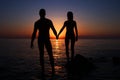 Vacation couple walking on sunset beach together in love holding hands. Happy young couple silhouette on sunset. Royalty Free Stock Photo