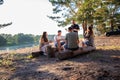 Vacation friends in the summer on the banks of the river in nature. Kindling a fire and cooking in the forest. Tourism Royalty Free Stock Photo