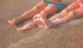 Vacation and holidays concept. Feet of two young girls relaxing on beach enjoying sun and sea on sunny summer day Royalty Free Stock Photo