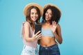 Vacation photo of two multiethnic girls wearing straw hats and s