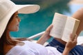 Vacation, relax and woman at pool with book, hat and lounge with happy summer travel on hotel patio. Holiday, deck chair Royalty Free Stock Photo