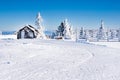 Vacation rural winter background with small wooden alpine house, white pines, fence, snow field, mountains