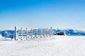 Vacation rural winter background with white pines, fence, snow field, mountains