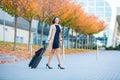 Vacation. Smiling female passenger proceeding to exit gate pulling suitcase through airport concourse