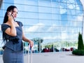 Vacation. Smiling female passenger proceeding to exit gate pulling suitcase through airport concourse Royalty Free Stock Photo