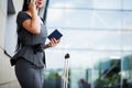 Vacation. Smiling female passenger proceeding to exit gate pulling suitcase through airport concourse Royalty Free Stock Photo