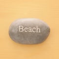 vacation and summer image of stone with word BEACH over yellow wooden background. Royalty Free Stock Photo