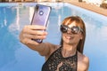 Selfie from the smartphone of a young young girl in a black bathing suit. Vacation and technology. Colorful portrait of pretty Royalty Free Stock Photo