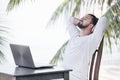 Vacation and technology. Work and travel. Young bearded man using laptop computer while sitting at beach cafe bar. Royalty Free Stock Photo