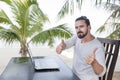 Vacation and technology. Work and travel. Young bearded man using laptop computer while sitting at beach cafe bar and Royalty Free Stock Photo