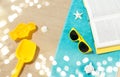Sunglasses, sand toys and book on beach towel Royalty Free Stock Photo