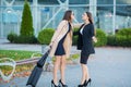 Vacation. Two happy girls traveling abroad together, carrying suitcase luggage in airport Royalty Free Stock Photo