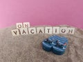 On vacation written on sand with blue flip flops and pink background