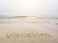 Vacation written in a sandy tropical beach. Words written in sand against the sea in sunny day. Summer vacation weekend concept.