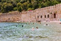 Vacationers bathe and sunbathe against the background of the ancient fortress wall Alanya, Turkey