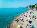 Vacationers on the free sandy and pebble Capo San Donato or Castelleto Pier Beach. Finale Ligure, Italy. Copy space