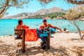 Vacationers relaxing on bench and watching to the Pandamos beach in Halki island in Greece
