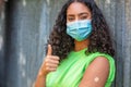 Vaccinated African American female young woman wearing face mask and vaccine band aid Royalty Free Stock Photo