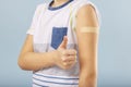 Vaccinated boy gesturing with thumbs up, showing hand with plaster cast after injection of coronavirus vaccine. Start of