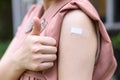 Vaccinated Woman Gesturing Thumb Up and Showing Arm With Plaster Bandage After Coronavirus Vaccine Injection. Royalty Free Stock Photo