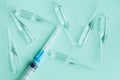 Medical syringe and glass ampules with vaccine or medicine on blue background, top view, flat lay