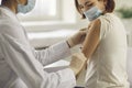Young woman in face mask getting Covid-19 or flu antiviral vaccine at doctor`s office