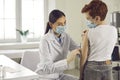 Professional nurse in a medical face mask giving a flu shot to her little patient Royalty Free Stock Photo