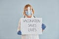 Vaccination saves lives banner. Senior female doctor in white coat is standing indoors