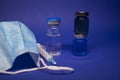 Vaccine bottle phial with no label, medical syringe with injection needle, blue medical mask . isolated on blue background. cure.