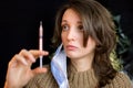 Vaccine concept. Female portrait of caucasian woman with face mask holding a syringe and looking at it on black Royalty Free Stock Photo