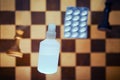 Vaccine pills and retro chess board with chess pieces, king and queen. Concept of problems of intellectual game, politics and