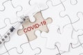 Vaccine and syringe injection with COVID-19 text on jigsaw