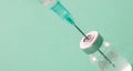 Vaccine vial dose and syringe against green background