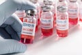 Vaccine vial in human hand closeup and many glass bottles