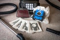 Vacum cleaner sitting on the floor with new and old dust bags and hepa filter in the back.