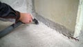 Vacuum cleaner construction on the background of concrete walls and floors. A worker removes dust with a vacuum cleaner from a Royalty Free Stock Photo