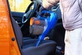 Vacuum cleaner in hands of driver. Cleaning of interior of automobile with blue vacuum cleaner. Car textile seats is regular clean Royalty Free Stock Photo