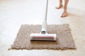 Vacuum cleaning on a beige rug on the floor and next to woman& x27;s leg, house cleaning, vacuuming an apartment, clean Royalty Free Stock Photo