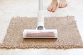 Vacuum cleaning on a beige rug on the floor and next to woman's leg, house cleaning, vacuuming an apartment, clean Royalty Free Stock Photo