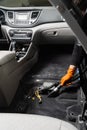 Vacuum cleaning of dirty car floor with removed seats in detailing service. Worker of detailing service is using vacuum Royalty Free Stock Photo