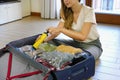 Vacuum clothing storage compressed package. Beautiful unidentified woman using vacuum pump saving space in her luggage sitting on Royalty Free Stock Photo