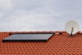 Vacuum collectors - solar water heating system on red roof of the house with satellite Royalty Free Stock Photo