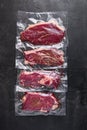 Vacuum packed organic raw beef alternative cuts: top blade, rump, picanha, chuck roll steaks, over black textured background, top Royalty Free Stock Photo
